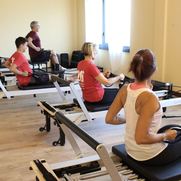 Esercizio di gruppo con pilates reformer, adatto per giovani ed adulti