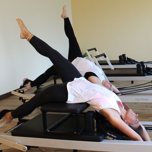 Coppia di ragazze che esegue esercizi per la schiena con pilates reformer